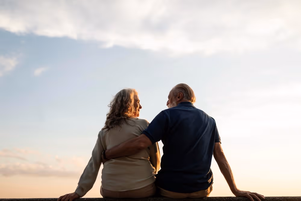 Un couple regarde l’horizon au coucher du soleil, illustration de la préparation de la retraite.