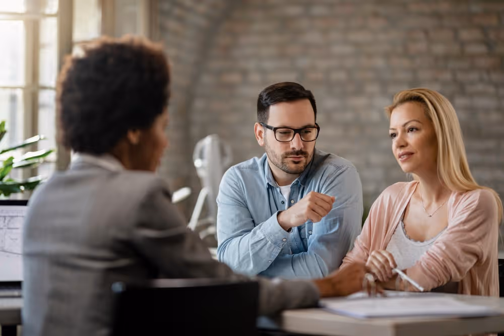 Un homme et une femme échangent autour d’un bureau, illustration des démarches de succession entre frère et sœur.
