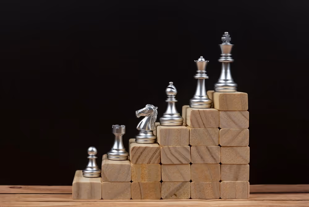 Pièces d’échecs sur des blocs en bois, illustration des critères de choix d’un cabinet de gestion de patrimoine.
