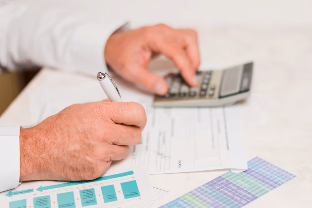 Une personne remplit un formulaire avec une calculatrice, illustration de la simulation des droits de succession.