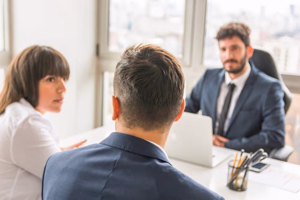Trois personnes discutent autour d’une table, illustration du calcul des droits de succession selon le lien de parenté.