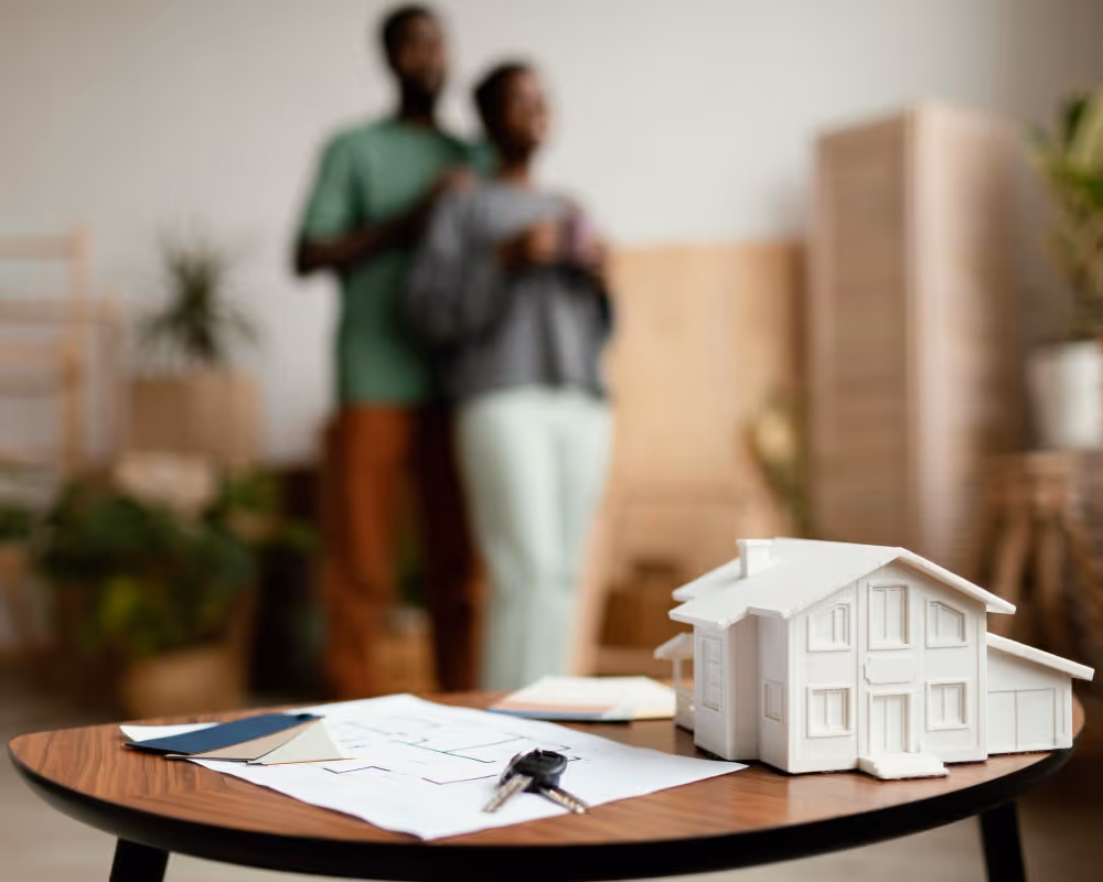 Maquette de maison, clés et documents devant un couple, illustration de l’investissement en SCPI à crédit.