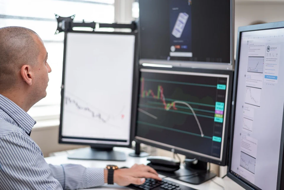 Un professionnel analyse des graphiques financiers sur ses écrans.