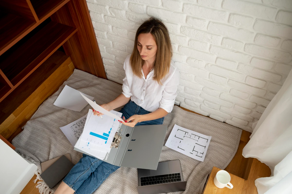 Une femme examine des documents et des plans, illustration de la fiscalité Airbnb et des revenus locatifs.