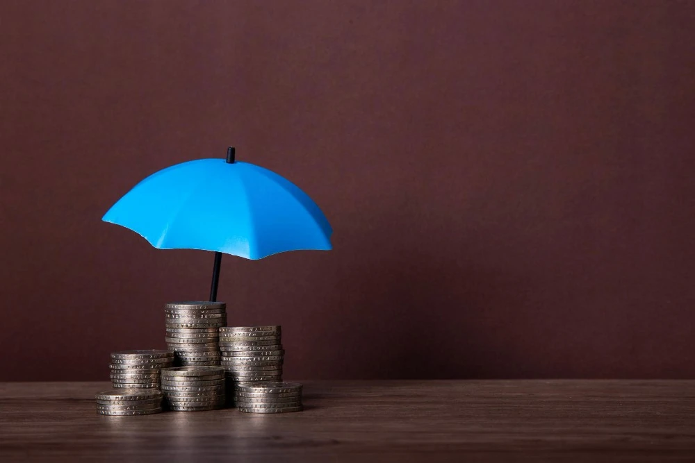 Piles de pièces sous un parapluie, illustration de l’estimation du rendement d’une assurance vie.