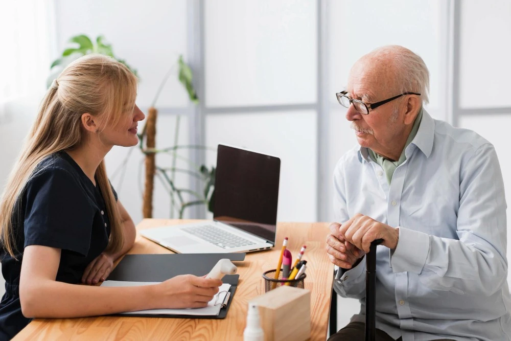 Un homme âgé échange avec une femme autour d’un bureau, illustration d’une réflexion sur l’avance sur héritage.