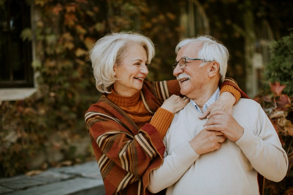 Un couple âgé sourit dans un jardin, illustration de la réflexion sur une donation après 70 ans.