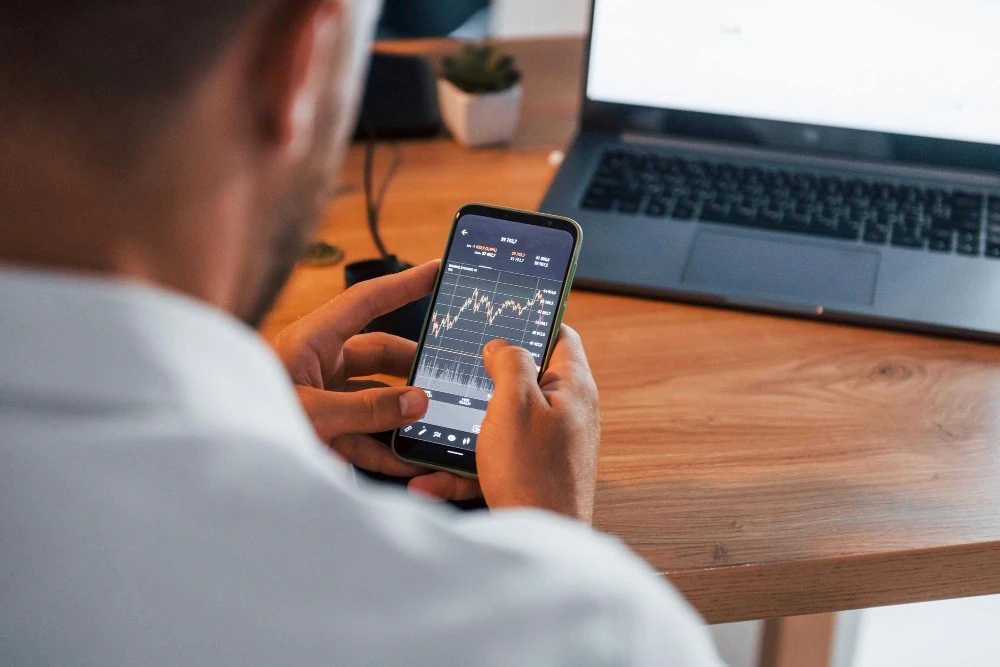 Un homme consulte un graphique sur son téléphone, illustration du revenu mensuel d’un placement de 300 000 euros.