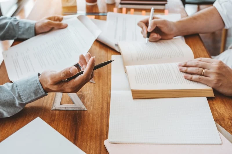 Plusieurs personnes examinent et signent des documents, illustration d’un investissement en SCPI en assurance vie.