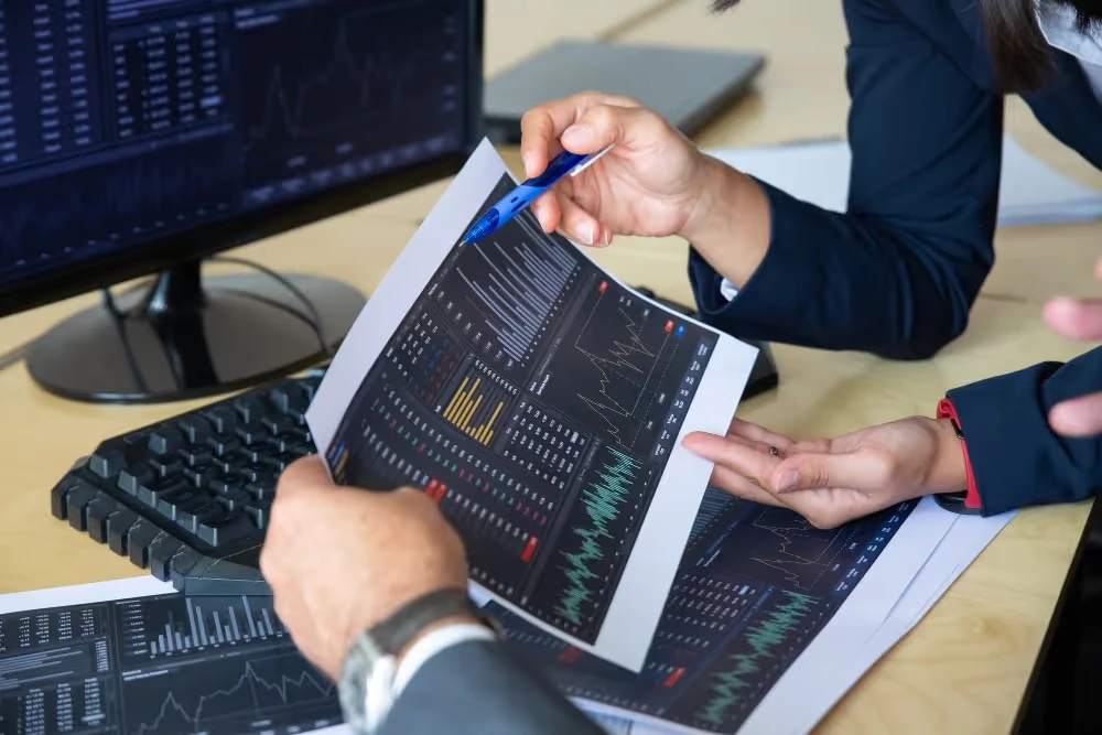 Deux personnes examinent des graphiques financiers imprimés, illustration du choix d’un ETF adapté à sa stratégie.
