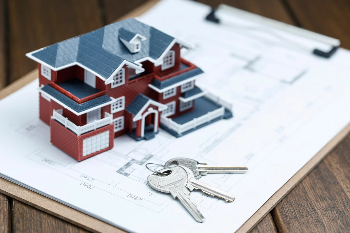 Maquette de maison et clés sur un plan, illustration du choix entre SCI et SCPI pour investir dans l’immobilier.