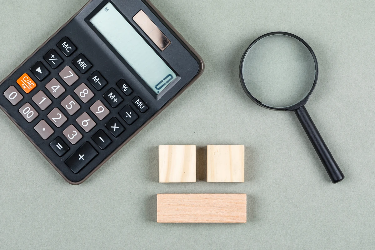 Calculatrice, loupe et blocs de bois illustrant l’analyse de la fiscalité des SCPI.