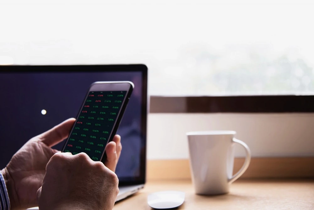 Cotations consultées sur un téléphone, illustration des revenus mensuels d’un placement de 50 000 euros.