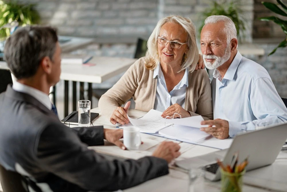 Un couple âgé échange avec un conseiller, illustration de la succession d’un contrat de capitalisation.