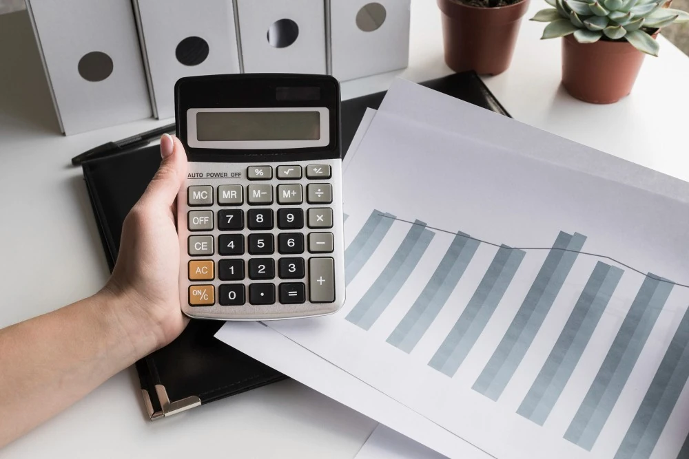 Calculatrice au-dessus d’un graphique en colonnes, illustration du calcul des intérêts composés d’un placement.
