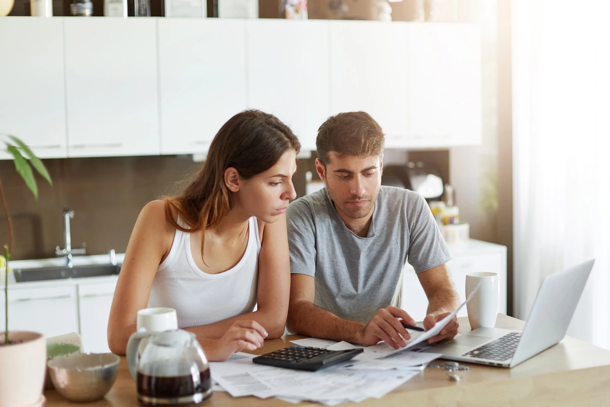 Un couple examine des documents près d’une calculatrice, illustration d’une simulation de rachat d’assurance vie.