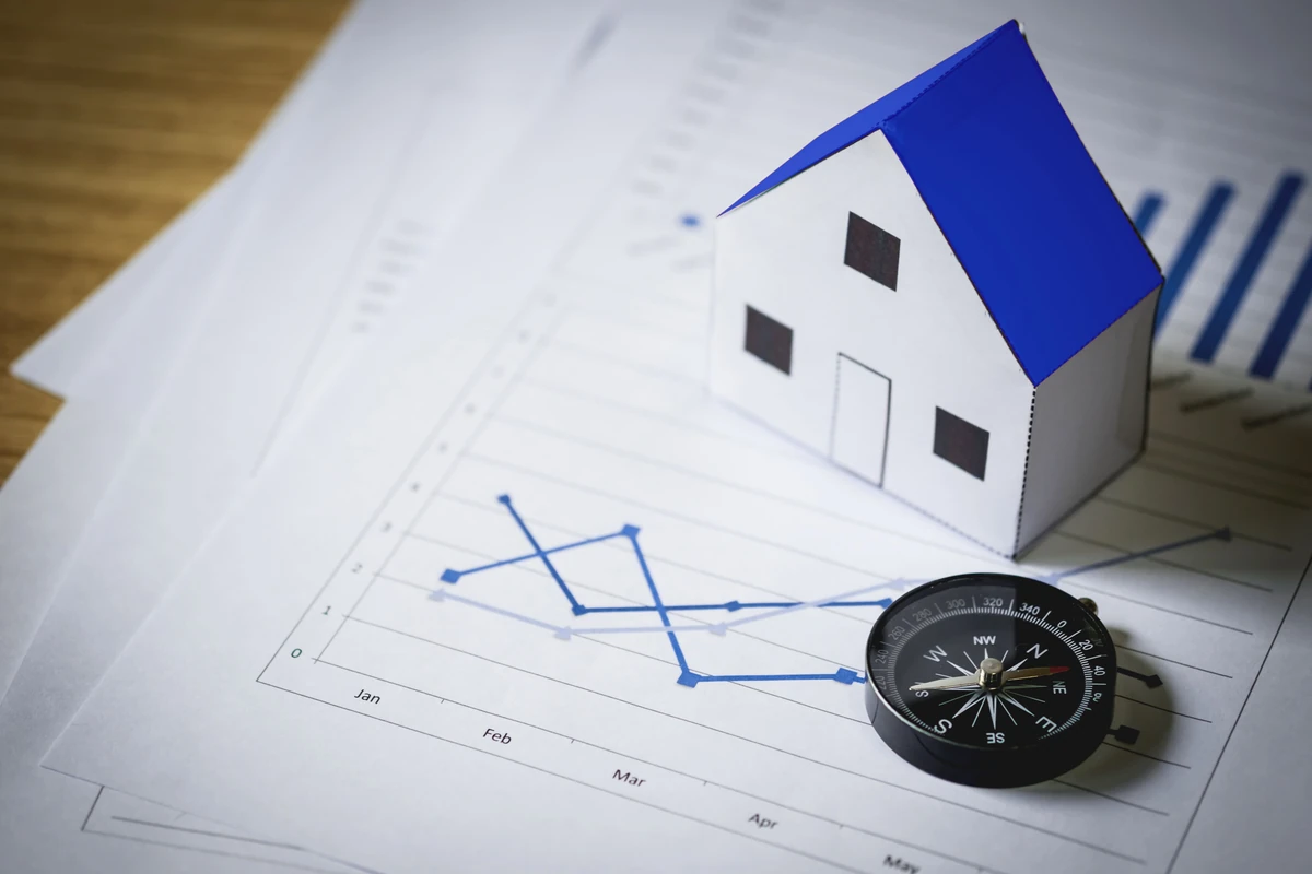 Maquette de maison et boussole sur des graphiques, illustration de l’analyse des risques d’un investissement en SCPI.