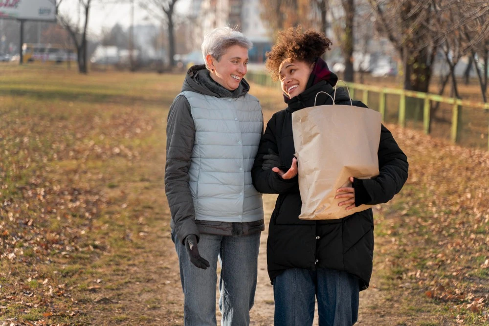 Deux femmes marchent ensemble dans un parc, illustration de la transmission familiale par donation simple.
