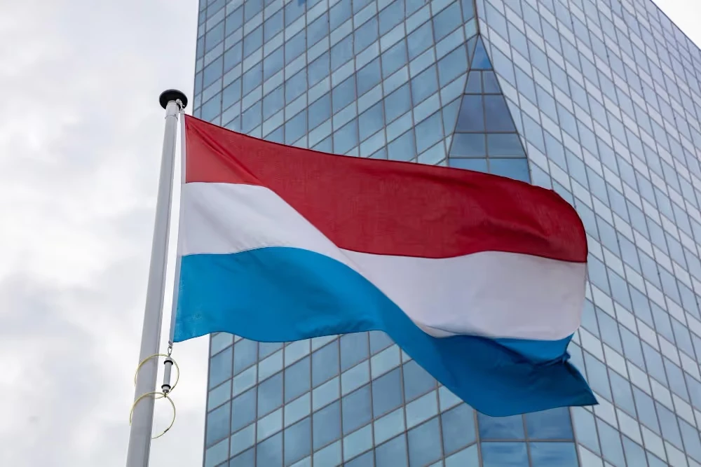 Drapeau du Luxembourg devant un immeuble vitré, illustration de l’assurance vie luxembourgeoise.