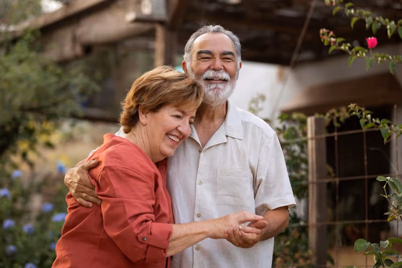 Un couple consulte un téléphone dans un jardin, illustration de l’article sur la donation d’une maison avec usufruit.
