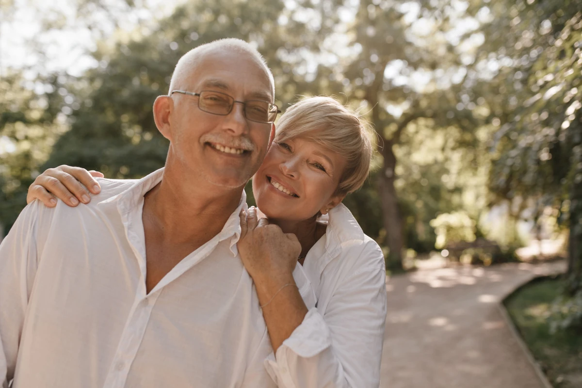 Un couple âgé sourit dans un jardin, illustration du choix des placements pour la retraite.