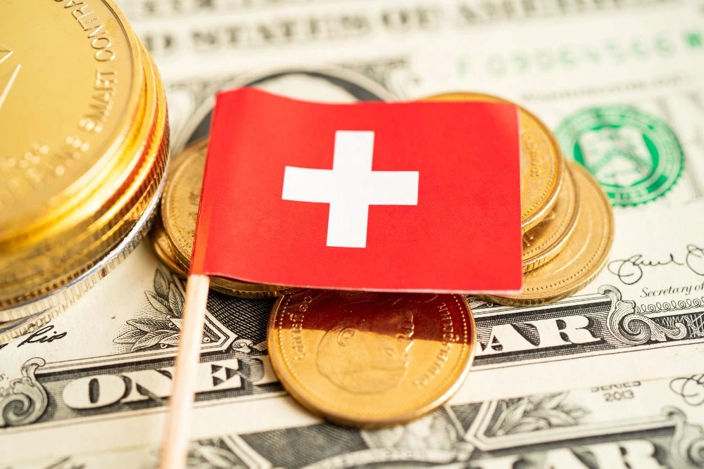 Drapeau suisse sur des pièces et des billets, illustration des démarches pour ouvrir un compte en Suisse.